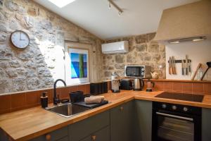 una cucina con un lavandino e un orologio a parete di "Historic Stone Loft" - ZF Stari Grad a Stari Grad (Cittavecchia)