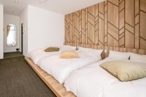 a row of white beds in a room at LUX by Hotel BAL in Fukuoka
