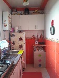 a small kitchen with red tiles and a refrigerator at casa martil 2 in Martil