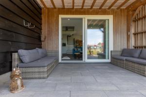 a patio with two couches and a sliding glass door at Welcome in - Vakantiewoning Jikkemien met terras, vrij uitzicht en huisdiervriendelijk in Koudekerke