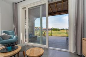 a living room with a sliding glass door leading to a patio at Welcome in - Vakantiewoning Jikkemien met terras, vrij uitzicht en huisdiervriendelijk in Koudekerke