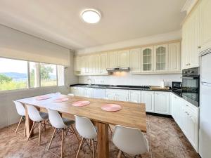 a kitchen with a wooden table and white cabinets at Casa para 10 personas junto a la playa entre Combarro y Sanxenxo "Casa Saqueta" in Pontevedra