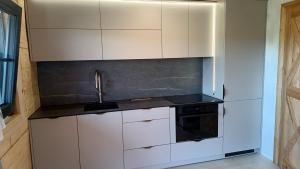 a kitchen with white cabinets and a black appliance at Drewno i Len in Debina
