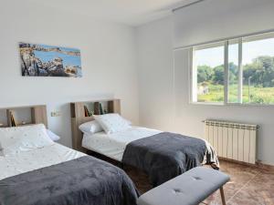 two beds in a room with a window at Casa para 10 personas junto a la playa entre Combarro y Sanxenxo "Casa Saqueta" in Pontevedra