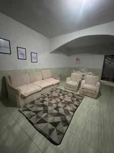 a living room with a couch and two chairs and a rug at Casa temporada in Rio das Ostras