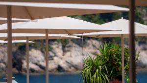 a group of white umbrellas sitting on a beach at Rixos Premium Dubrovnik in Dubrovnik