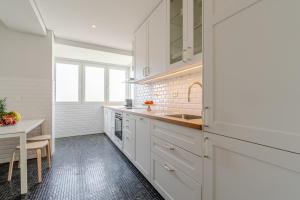 a white kitchen with a sink and a table at HostWise - Bright & Spacious Flat w/ Garage in Porto