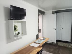 a living room with a table and a tv on a wall at Basaltic Guest House in Achadinha
