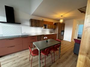 a kitchen with a table and red chairs in it at Maison pilotis 6 pers 50m mer in Les Moutiers