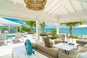 a living room with white furniture and the ocean at Villa Turquoise Turks Caicos in Leeward