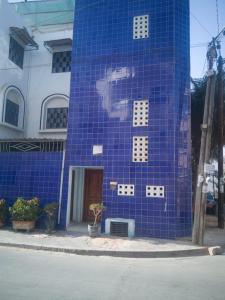 un edificio piastrellato di blu con un volto dipinto sopra di Résidence SKS Hébergement a Dakar