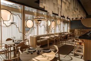 a restaurant with tables and chairs and large windows at The Chedi Luštica Bay in Tivat