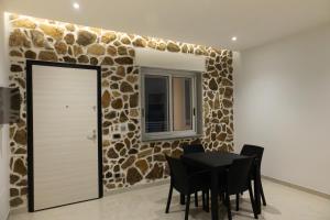 a dining room with a table and a stone wall at LA PERLA MARE- Wi-fi and free parking in Capo Vaticano