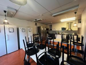 a kitchen with white appliances and black chairs at Rentalux Hostel - Budget Double & Single rooms in Timrå