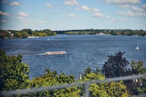 a boat on a river with boats in the water at Hotel Atlantic Hamburg, Autograph Collection in Hamburg