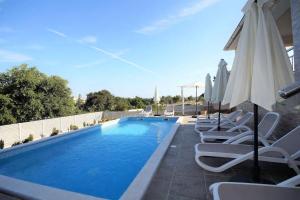 a swimming pool with lounge chairs and an umbrella at Villa Anna in Medulin