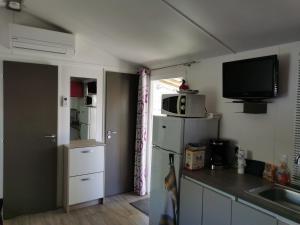 a kitchen with a refrigerator and a tv on the wall at Mobile home grande terrasse à Canet in Canet-en-Roussillon