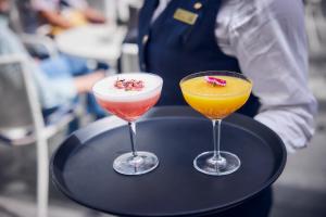 two cocktails on a black tray with a waiter at Hotel Atlantic Hamburg, Autograph Collection in Hamburg