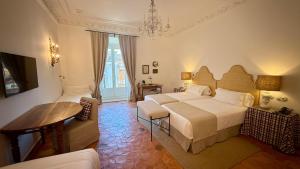 um quarto de hotel com duas camas e uma mesa em Casa Pizarro Hotel em Cáceres