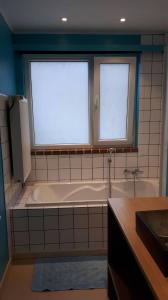 a bathroom with a bath tub and two windows at Le Coeur sur la Main in Namur