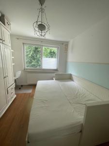 1 dormitorio con 1 cama blanca grande en una habitación con ventana en Reihenhaus inmitten der Stadt, en Rostock