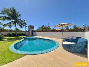 a swimming pool with two chairs and an umbrella at Bella Arte 2 Rooftop in Aquiraz
