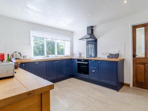 a large kitchen with blue cabinets and a window at 3 Bed in Syderstone 78973 in Syderstone