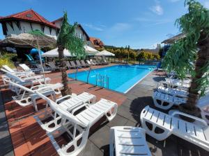 a group of white lounge chairs and a swimming pool at Bartpol Family & SPA in Gródek Nad Dunajcem