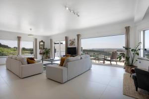 a living room with white furniture and large windows at Peace House Lourinhã in Lourinhã