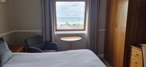 Schlafzimmer mit einem Bett und einem Fenster mit einem Stuhl in der Unterkunft White Sands Hotel in Ballyheigue