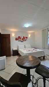 a bedroom with a bed and a table and chairs at Pousada Recanto da Mata in Marechal Floriano