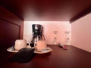 a counter with a coffee maker and glasses on it at Hotel y termales Las Heliconias in Zetaquira