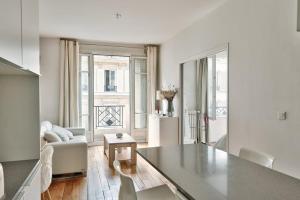 a white living room with a table and a couch at Spacieux et lumineux appartement in Paris