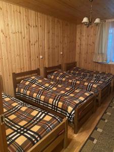 a group of three beds in a room with wooden walls at Shatili ( Green House ) in Shatili