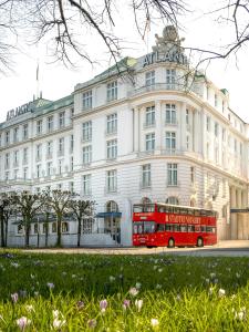 a red double decker bus parked in front of a building at Hotel Atlantic Hamburg, Autograph Collection in Hamburg
