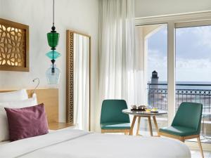 a bedroom with a bed and two chairs and a table at The Chedi Luštica Bay in Tivat