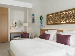 a bedroom with a large white bed with purple pillows at The Chedi Luštica Bay in Tivat