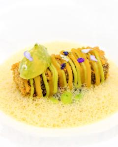 a plate of food with a waffle with yellow icing at Hotel Atlantic Hamburg, Autograph Collection in Hamburg