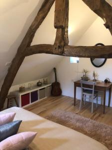 une chambre avec un lit, une table et une guitare dans l'établissement l'atelier de Sophie, à Longueville
