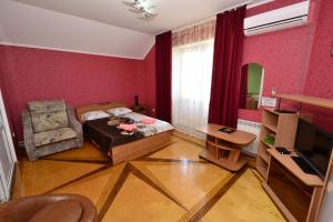 um pequeno quarto com uma cama e uma cadeira em Vek Guest House em Anapa