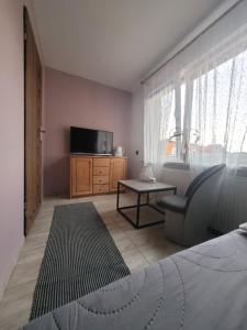 a bedroom with a bed and a tv and a chair at Pokoje gościnne Ustronie Morskie - 260m do plaży in Ustronie Morskie