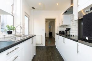 a kitchen with white cabinets and black counter tops at K Suites - Granville Avenue in Long Eaton
