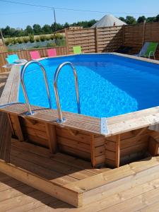 a swimming pool with a wooden deck next to a swimming pool at Yourte - Terracotta - Climatisée -Les Belles Ouvrières in Clermont-Créans