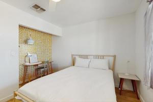 Un dormitorio con una cama blanca y un escritorio. en Burrobrush Terrace, en Joshua Tree