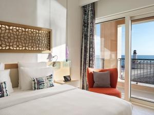 a bedroom with a bed and a chair and a window at The Chedi Luštica Bay in Tivat