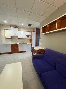 Una sala de estar con un sofá azul y una cocina. en Apartment Autovia Bormujos, en Bormujos