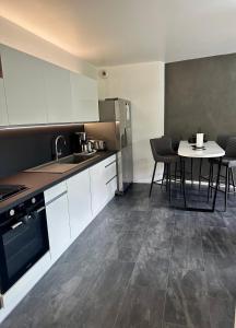 a kitchen with white cabinets and a table with chairs at Royal Standing- Terrasse & Parking Privé in Évian-les-Bains +3 photos