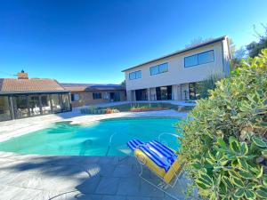 a swimming pool with two lounge chairs in front of a house at On Point Tranquil Garden Constantiaberg in Sweet Valley