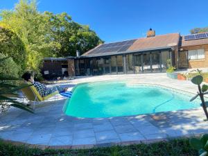 a person sitting in a chair next to a swimming pool at Tranquil Garden Constantiaberg in Sweet Valley