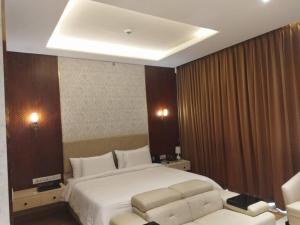 a bedroom with a large white bed and a couch at Leela Lifestyle Apartment in Bangalore in Bengaluru